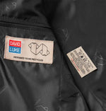 Close-up of the David Luke School Eco Blazer interior showing two sewn-in labels: a David Luke brand patch on the left and a care instruction label on the right.
