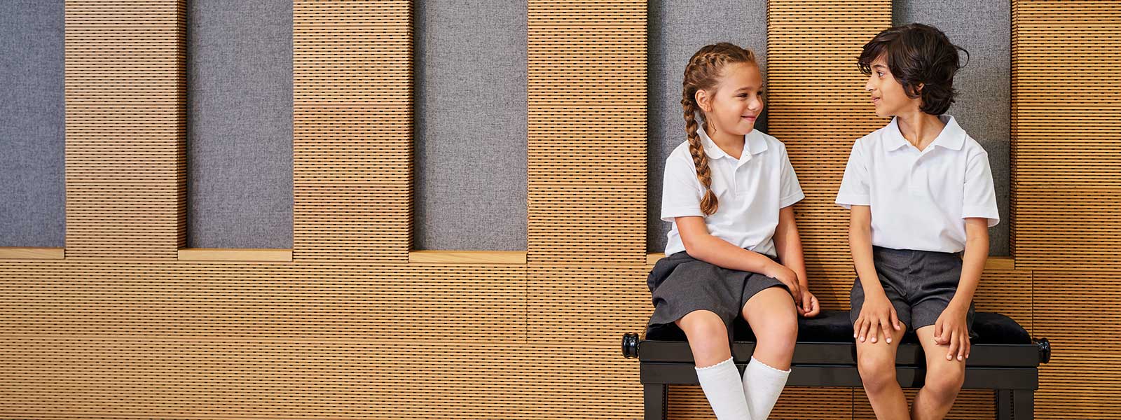 Two primary school children wearing white polo shirts